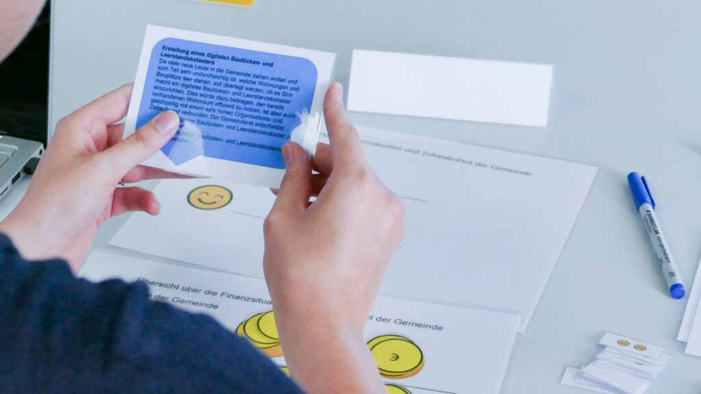 Blick über die Schulter einer Spielerin, die gerade eine blaue Ereigniskarte in der Hand hält