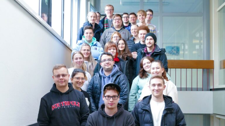Die knapp 20 Studierenden des Jahrgangs DVM21 beider Hochschulen mit den Lehrenden beim Gruppenfoto im Treppenhaus der Hochschule Kehl.