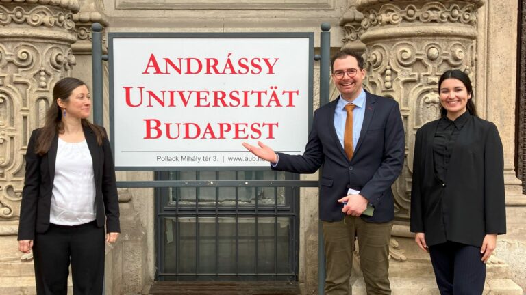 Die drei Mitglieder der Delegation der Hochschule Kehl vor dem Schild der Andrássy Universität Budapest.