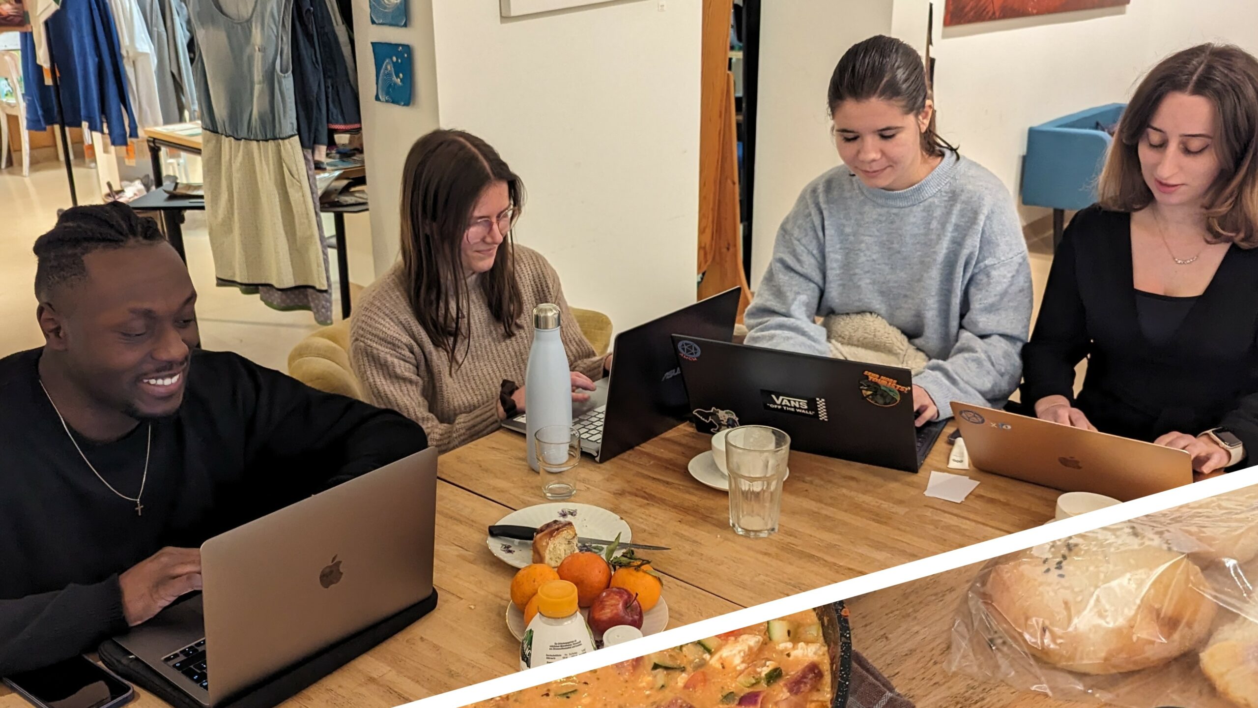 Vier Studierende sitzen gemeinsam an einem Tisch und arbeiten an ihren jeweiligen Laptops.